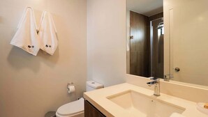 Ein modernes Badezimmer mit einem großen Spiegel, einem Waschbecken und einer Toilette.