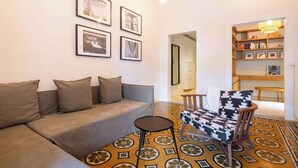 A living room with a sofa, a patterned rug, a chair, and a bookshelf. - w* | Elegant Stay in the Heart of Florence (Firenze)