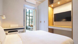 A bedroom with a bed, a piano, a television mounted on a wall, and a door leading to a balcony. - w* | Elegant Stay in the Heart of Florence (Firenze)