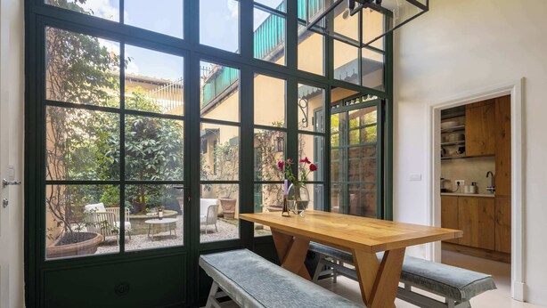 A room with a large window, a wooden table, and a bench. - w* | Elegant Stay in the Heart of Florence (Firenze)