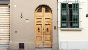 A wooden double door with a circular handle, a small window with green shutters, and a number plaque on the wall. - w* | Elegant Stay in the Heart of Florence (Firenze)