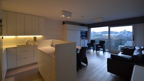 A modern apartment with a kitchen, dining area, and a balcony with a city view.