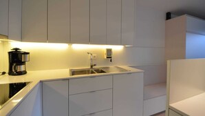 A modern kitchen with white cabinets, a stainless steel sink, and a coffee maker.