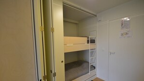 A room with a bunk bed, a door, and a wall with a notice.