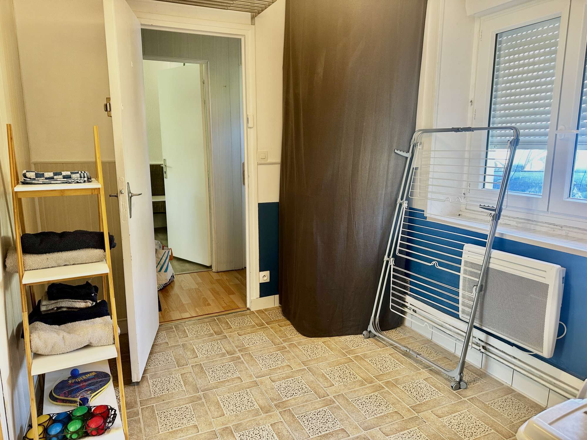 Una habitación con una estantería de madera escalonada, un radiador y una ventana con persianas.