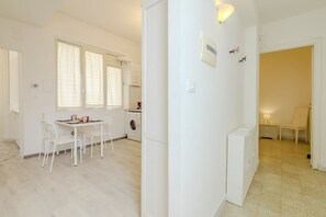 A modern, white interior with a dining area, kitchen, and laundry facilities. - Operetta View Apartment (ROMA)