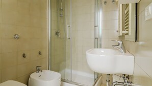 A bathroom with a glass-enclosed shower, a white sink, and a toilet. - Operetta View Apartment (ROMA)