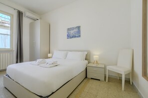 Une chambre d’hôtel avec un lit, une chaise, une table de chevet, un tableau et une fenêtre.