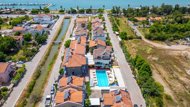 An aerial view of a coastal residential area with houses, a swimming pool, and a canal. - Aliş Hotel Fethiye (Fethiye)