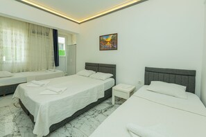 A hotel room with two beds, a small bedside table, a large window with curtains, and a painting on the wall. - Aliş Hotel Fethiye (Fethiye)