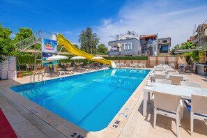 A swimming pool with a yellow slide, lounge chairs, and a covered seating area. - Aliş Hotel Fethiye (Fethiye)