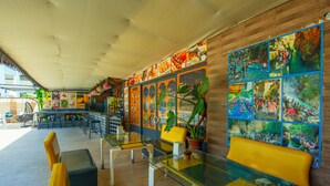 A restaurant with a glass table, yellow chairs, and a wooden wall with food images. - Aliş Hotel Fethiye (Fethiye)
