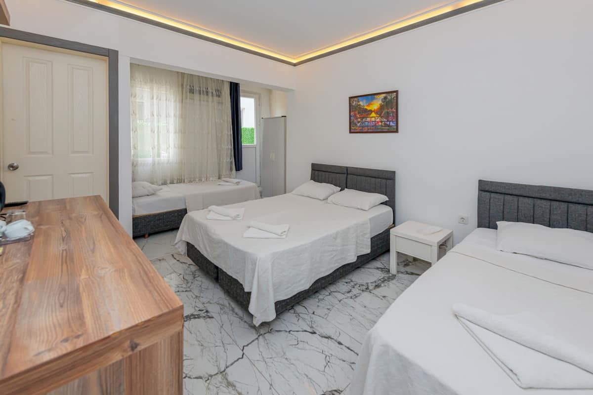 A hotel room with a wooden desk, two beds with white linens, a nightstand, and a painting on the wall.