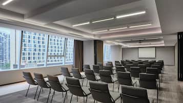 A conference room with rows of chairs, a projector screen, and large windows.