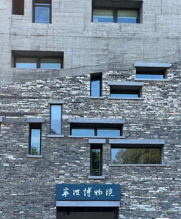 Fachada de edificio con textura de piedra y varias ventanas.