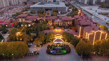 A high-rise hotel with multiple floors, a central courtyard with a fountain, and surrounding trees.