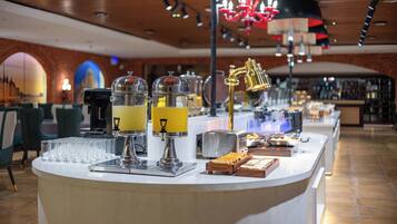 A bar area with a counter, two beverage dispensers, a golden faucet, and a red chandelier.