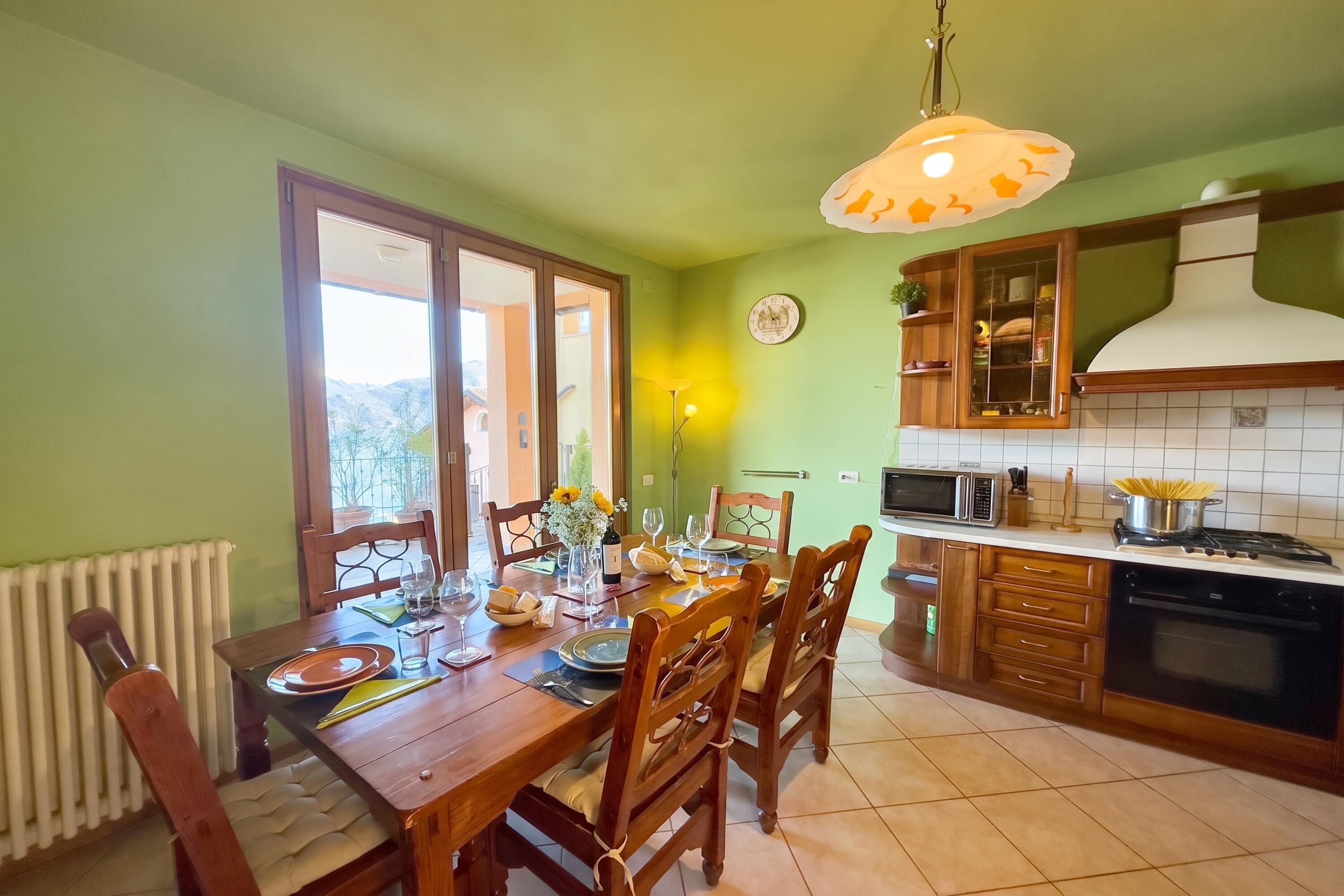 Un coin repas avec une table dressée pour quatre personnes, une cuisine équipée d’une cuisinière et d’un four à micro-ondes, et une vue par la fenêtre.