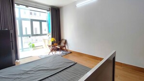 Una habitación moderna con cama, una mesita con un florero, una silla y vistas al exterior a través de amplios ventanales.