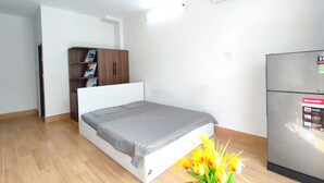 Una habitación pequeña y moderna con cama, armario empotrado, refrigerador y aire acondicionado de pared.