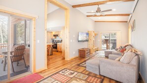 A spacious living area with a sofa, wooden flooring, and a large sliding glass door leading to an outdoor deck. - Chalet w 2nd Floor | Pool, Hot Tub (Breckenridge)