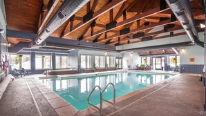 An indoor swimming pool with a wooden ceiling, clear windows, and a lifeguard chair. - Chalet w 2nd Floor | Pool, Hot Tub (Breckenridge)