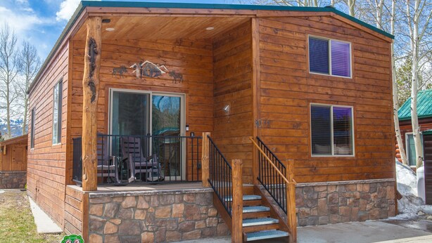 A wooden cabin with a stone foundation, a porch with outdoor seating, and a staircase leading to the entrance. - Chalet w 2nd Floor | Pool, Hot Tub (Breckenridge)