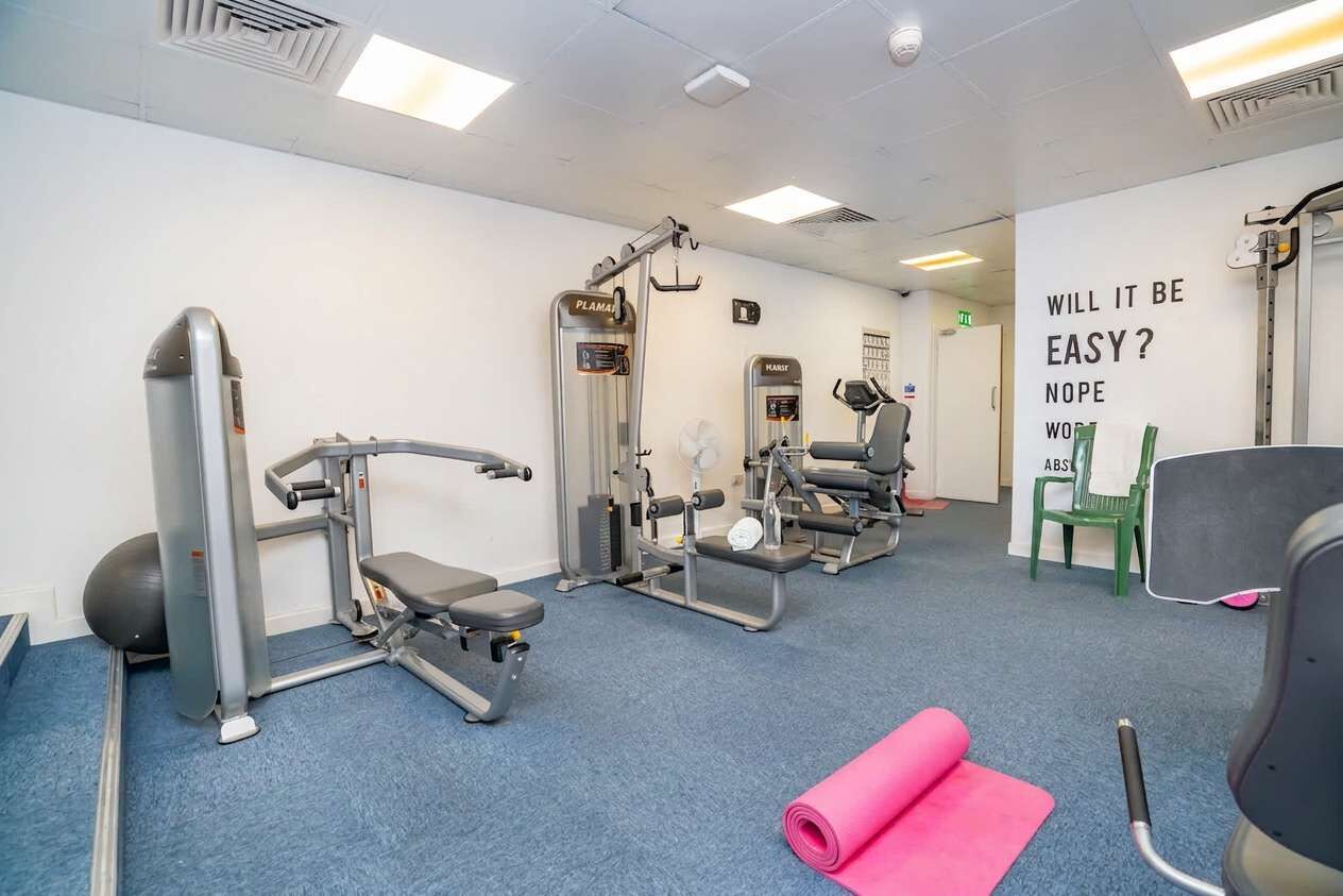 A gym with exercise equipment, a yoga mat, and motivational wall text.