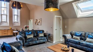 A modern living room with two sofas, a coffee table, and a large window with a skylight. - Chapel in Newquay near Towan Beach (Newquay)