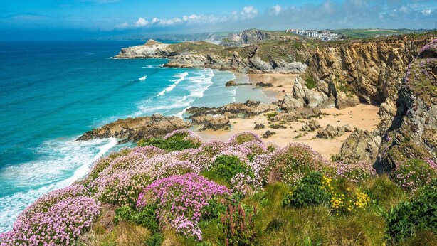 A coastal landscape with rocky cliffs, a sandy beach, and a clear blue sky. - Chapel in Newquay near Towan Beach (Newquay)