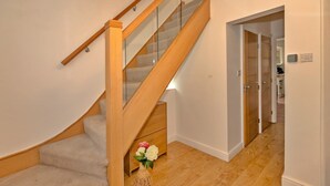 Un escalier en bois avec des rampes en verre et un petit meuble en bois au bas de l’escalier.