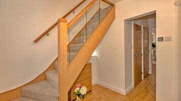 A wooden staircase with glass railings and a small wooden cabinet at the bottom.