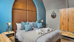 Ein Schlafzimmer mit einem großen Bett, einem Holzschrank und einem markanten, bogenförmigen Kopfteil.