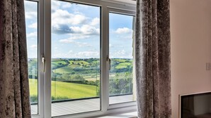 A room with a large window overlooking a green landscape.