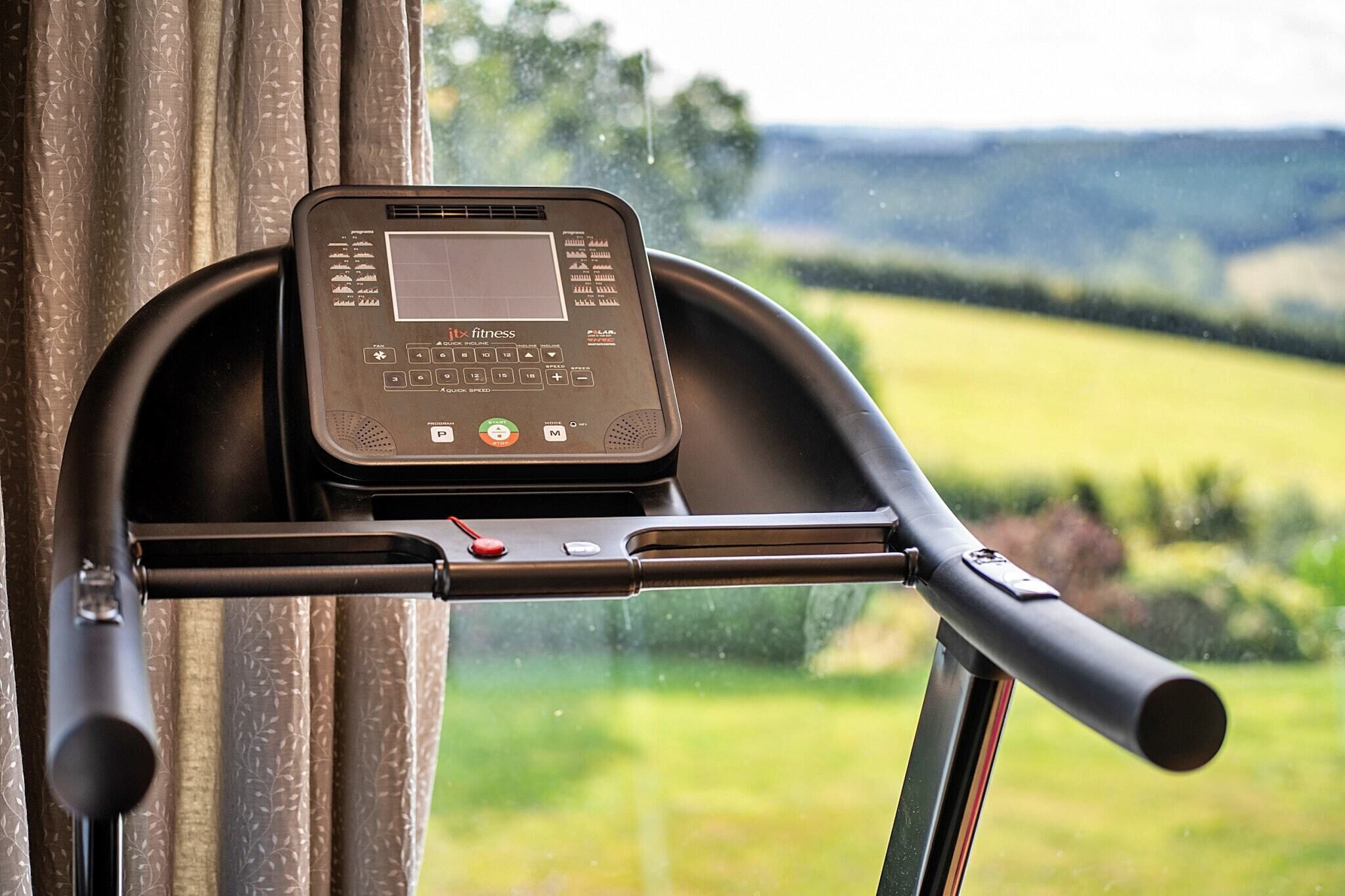 A stationary bike with a digital display, handlebars, and a window view of a green landscape.