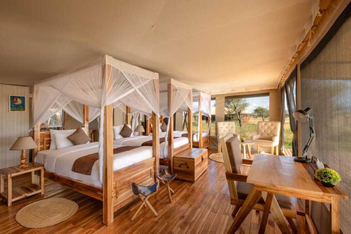 A room with a four-poster bed, wooden furniture, a desk, and a view of the outdoors.