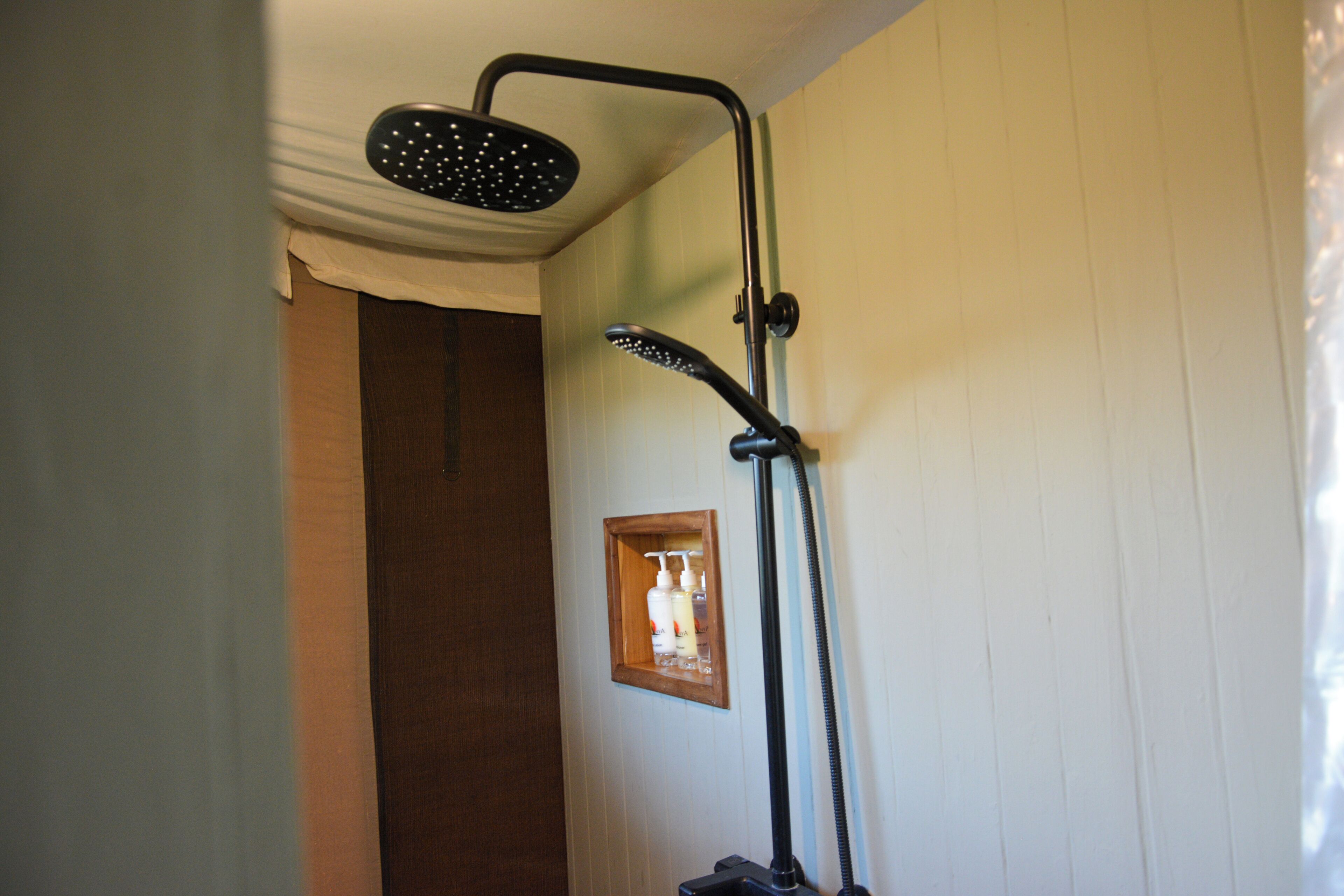 A shower with a handheld showerhead and a handheld vacuum attachment.