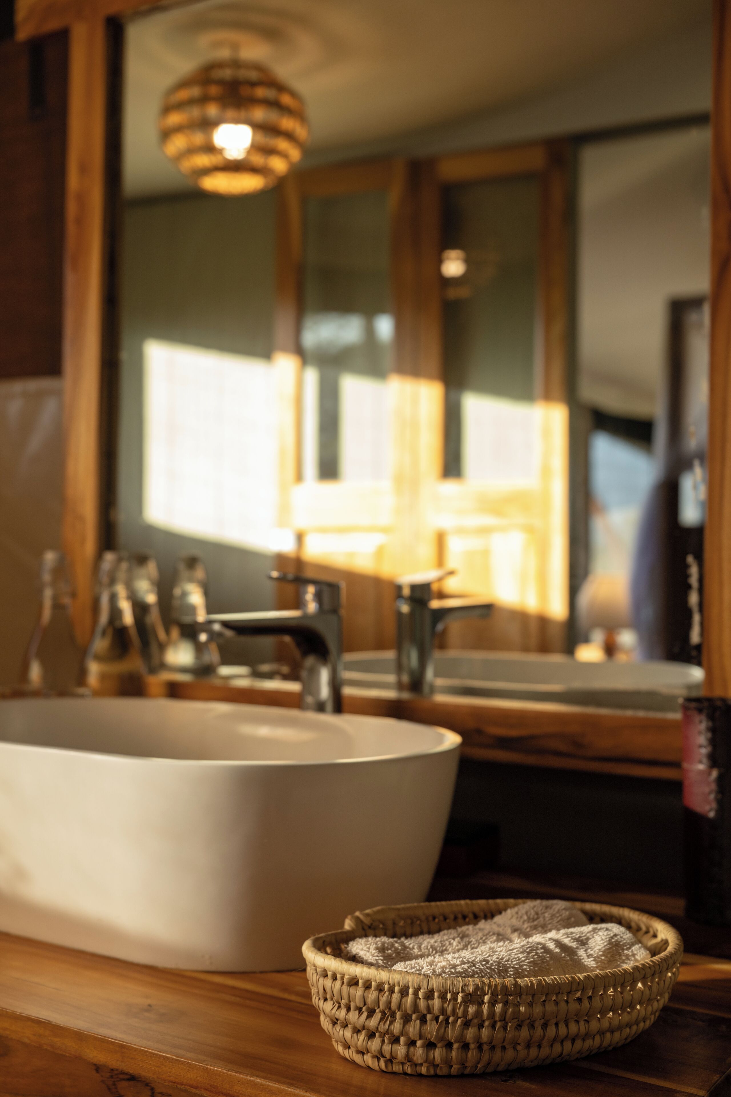 A bathroom with a large white sink, a mirror, and a woven basket on the counter.