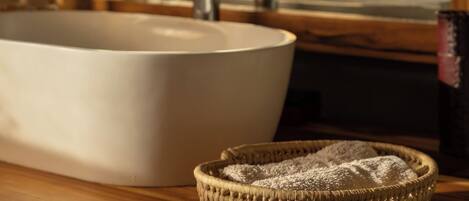 A bathroom with a large white sink, a mirror, and a woven basket on the counter.