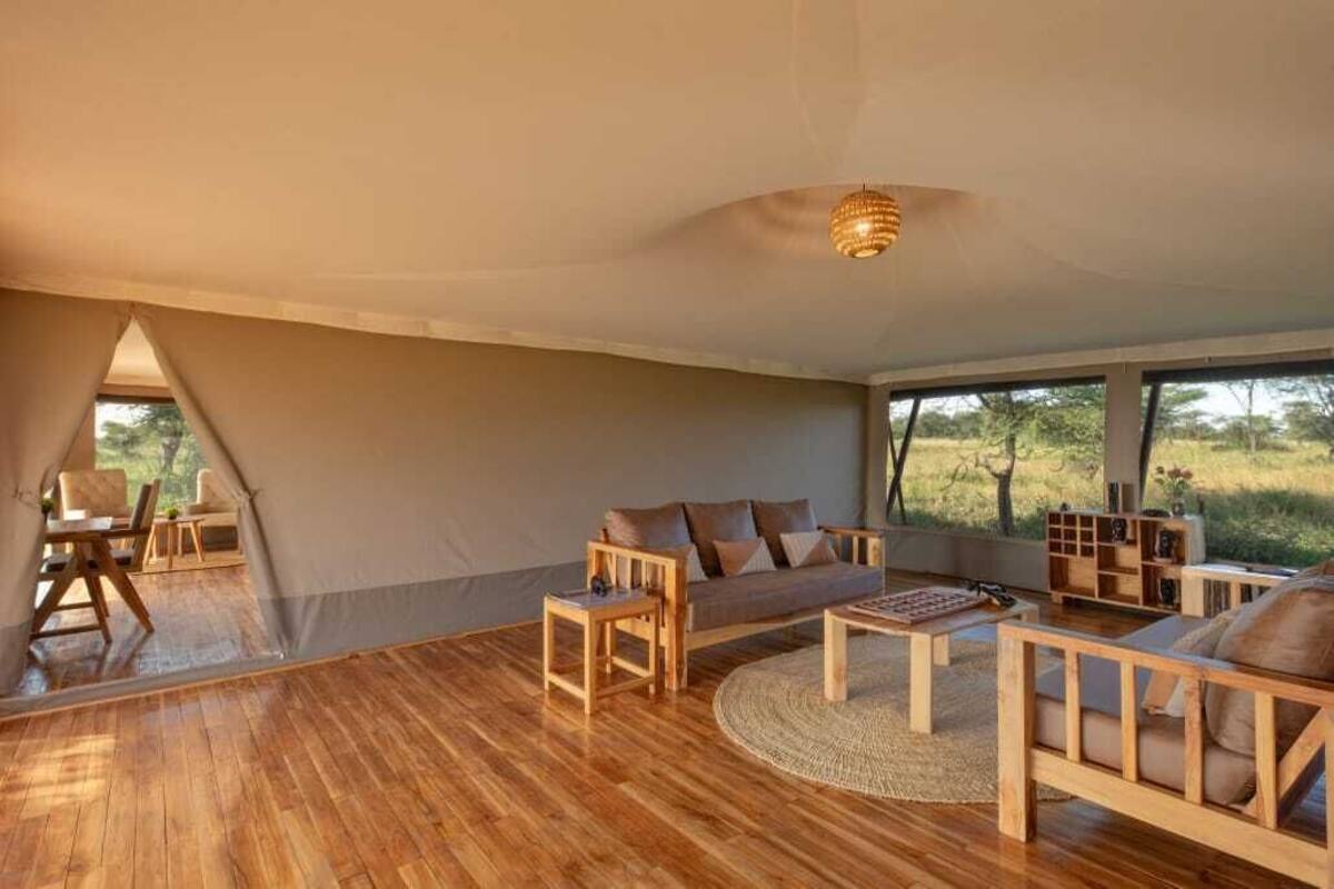 A spacious room with a large window, a sofa, a coffee table, and a wooden floor.