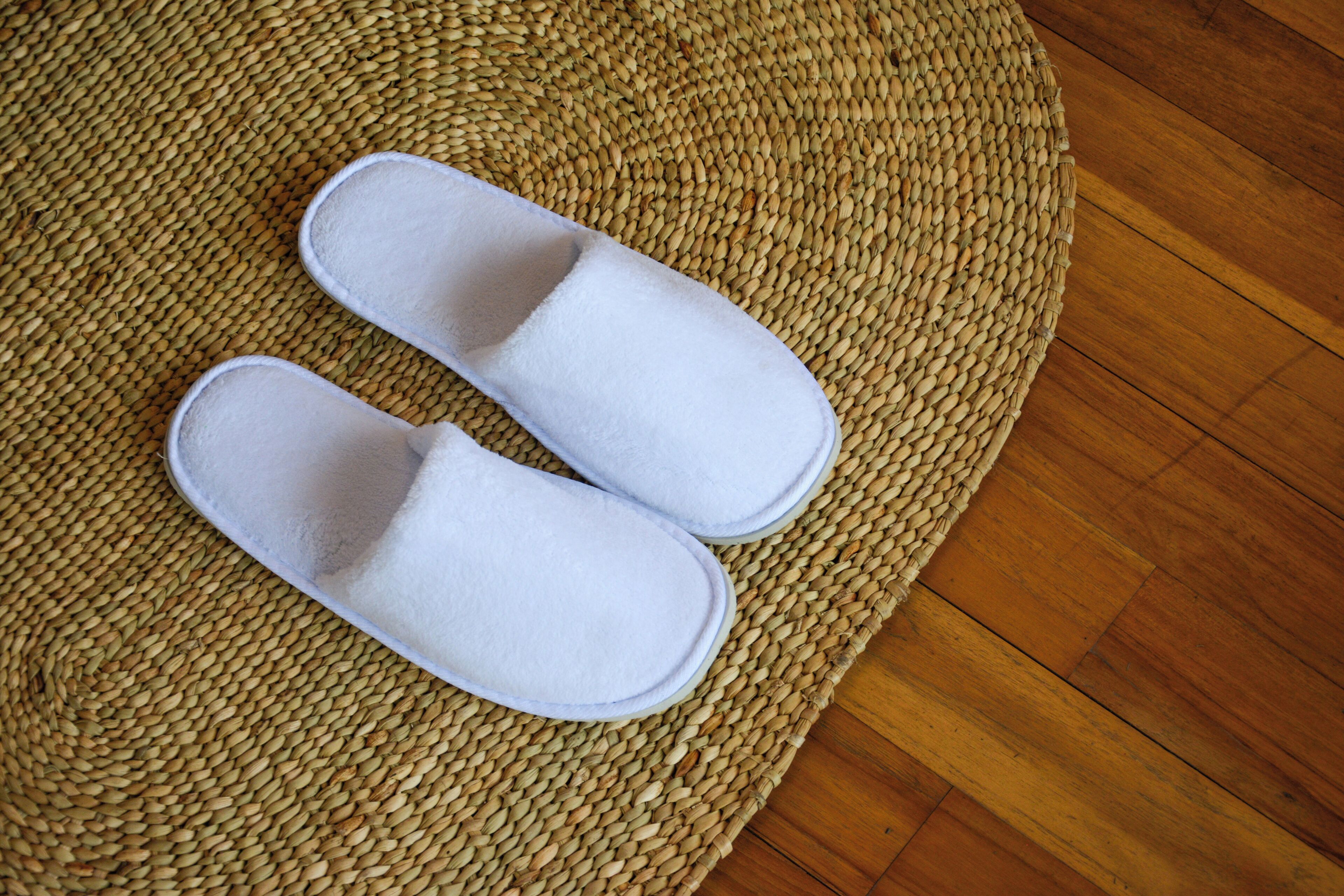 A pair of white slippers on a woven mat.