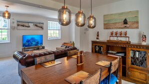 Un salon spacieux avec une table à manger en bois, un canapé en cuir et un téléviseur.