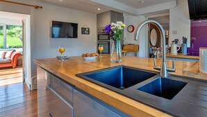 Een moderne keuken met een dubbele spoelbak, houten aanrecht en roestvrijstalen apparatuur.