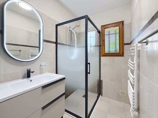 A modern bathroom with a glass-enclosed shower, a white sink, and a large mirror. - Villa vue mer piscine chauffée (Roquebrune-sur-Argens)