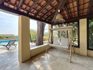 A covered outdoor area with a swing seat, a pool, and a view of the landscape. - Villa vue mer piscine chauffée (Roquebrune-sur-Argens)
