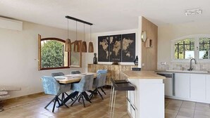 Eine moderne Küche mit einer zentralen Kochinsel, Barhocker und einem Essbereich mit Stühlen.