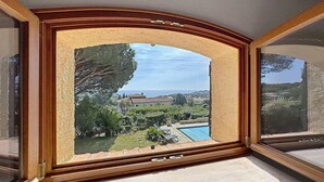 Ein Zimmer mit einem großen Bogenfenster mit Blick auf einen Swimmingpool und ein Gebäude in der Ferne.