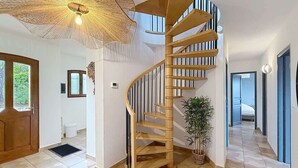 Ein geräumiges Zimmer mit Wendeltreppe, großem Fenster und einer Topfpflanze.