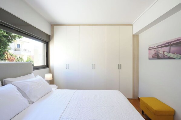 Un dormitorio con cama, ventana, armario y un cuadro en la pared.