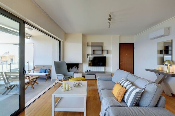 A modern living room with a grey sofa, a white coffee table, and a TV mounted on the wall.